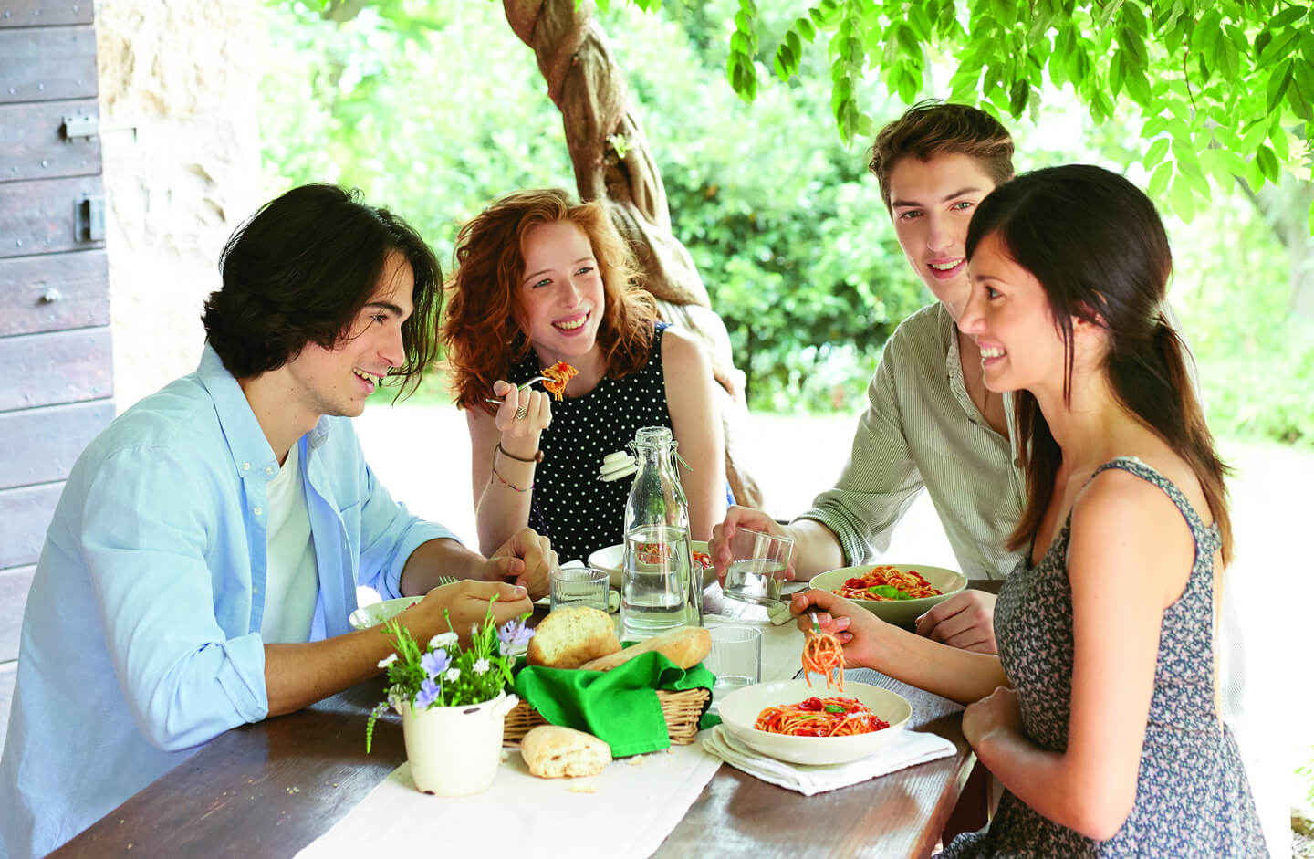 Gruppo di ragazzi che mangia a tavola felice